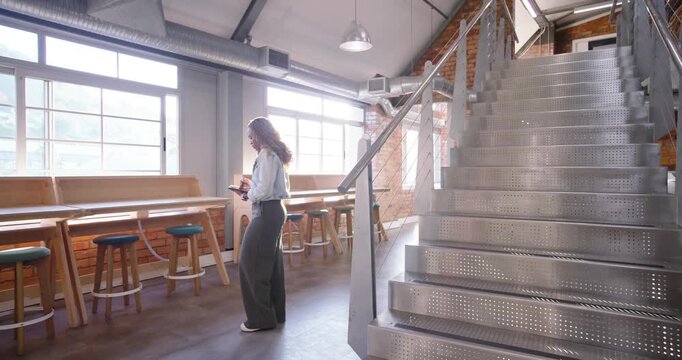 Midadult woman reading tablet, fixing jacket, heading up stairs while man descending copy space