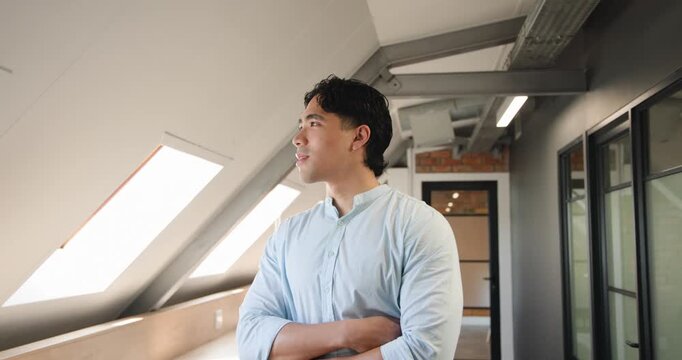 Adult Asian man in light blue shirt turning toward camera, smiling, prompted by skylight daylight