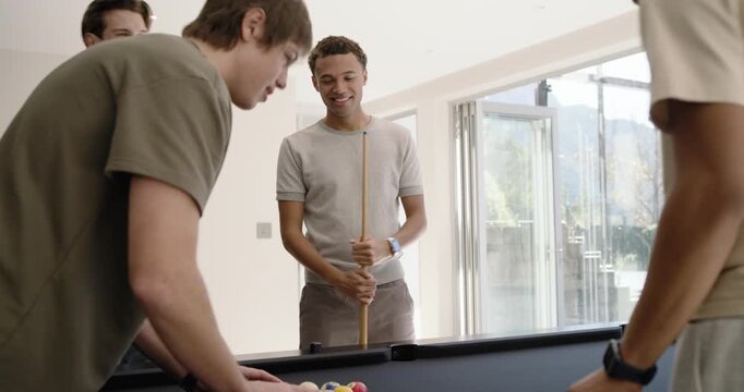 Diverse male friends placing triangular rack on black felt pool table, chatting, preparing break