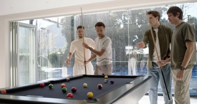 Diverse men checking racked balls, breaking, checking table for friendly game, cheering in rec room