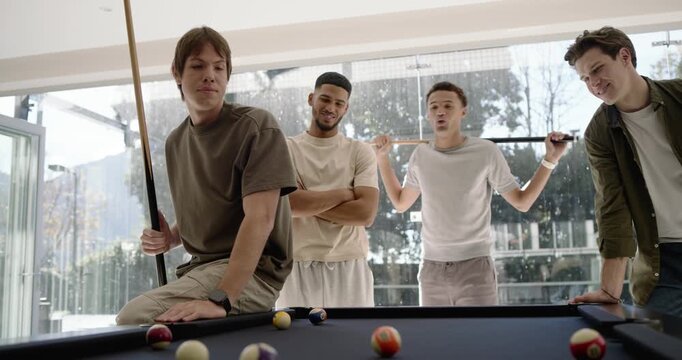 Diverse male friends watching shooter lining up, striking cue ball on black felt table for fun