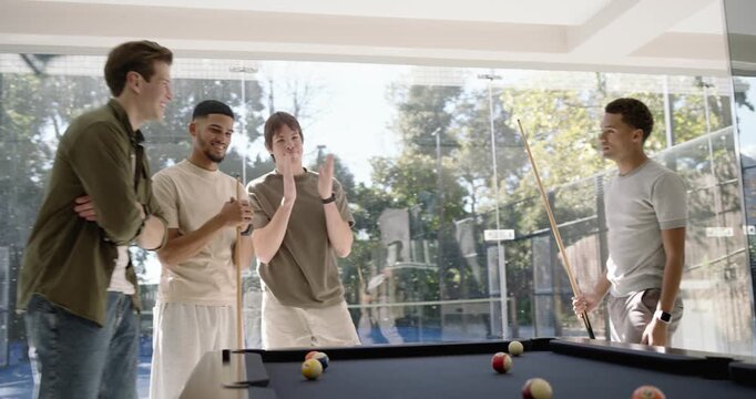 Four men watching, one taking cue shot on black felt table in glass-walled room, sparking rivalry