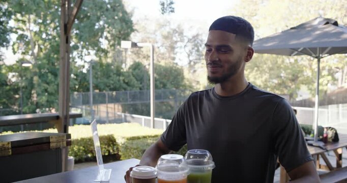 Man tapping watch while staff showing reader, bringing drinks to patron at cafe patio, copy space