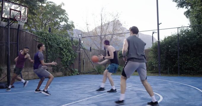 Four males in gear dribbling faking as defense closes passing basketball to score on outdoor court