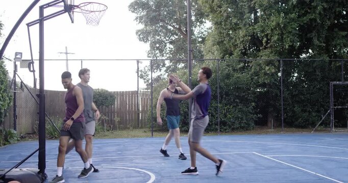 Four men retrieving basketball near baseline dribbling to hoop aiming to score on home court