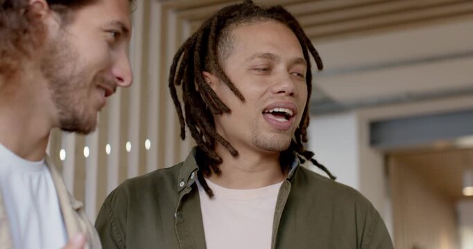 Team dreadlock man in olive coat listening chatting in office lobby by slats left man gesturing