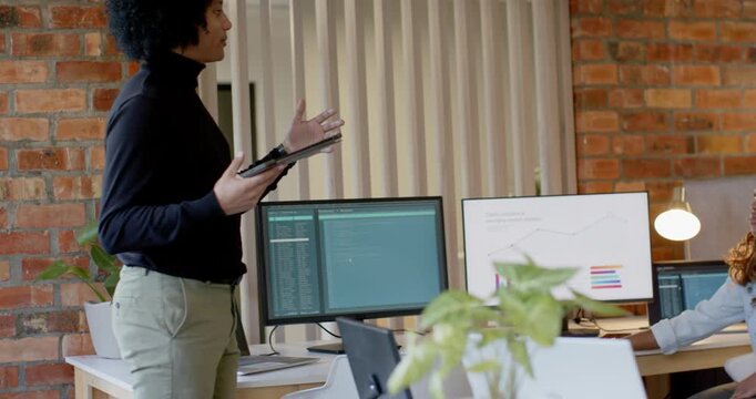 Diverse team watching lead stepping with tablet, gesturing, explaining charts in office, copy space