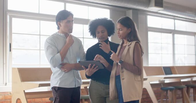 Diverse coworkers prompted by project update on tablet, collaborating and discussing at workspace