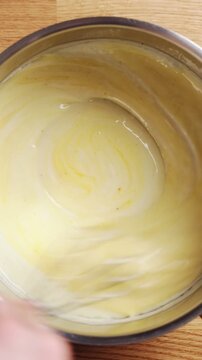 Chef mixes egg yolk into rich sauce in saucepan. Egg yolk blends smoothly, giving sauce silky texture and golden color. Egg yolk sauce recipe fits classic restaurant cooking style.
