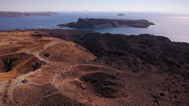 Aerial drone footage showing the Tholos Naftilos volcano and the nearby Palea Kameni island, famous for its therapeutic hot springs in the Santorini caldera, Greece.