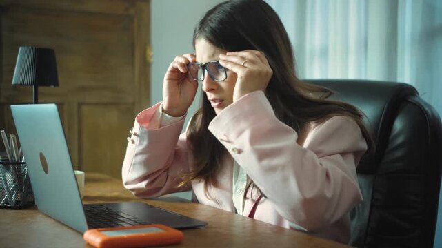 Young Hispanic businesswoman sitting in her office reviewing complex data on her laptop, looking confused and frustrated while trying to understand information and solve workplace problems.
