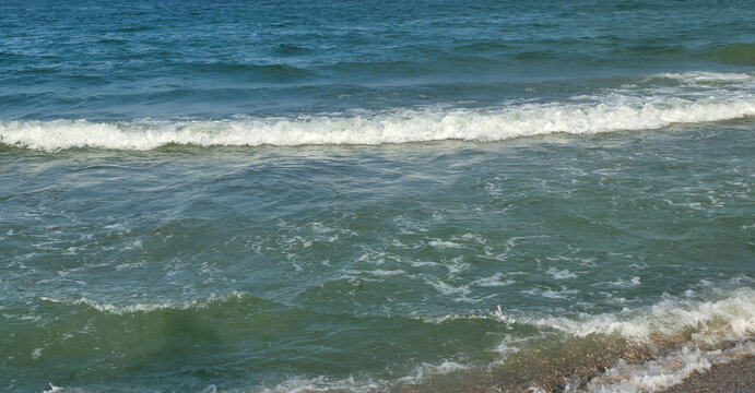 Ocean waves rolling onto the sandy beach shoreline