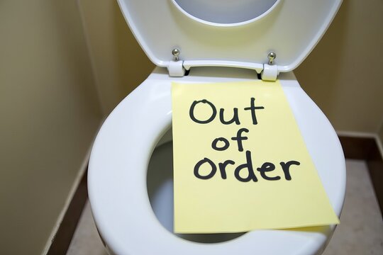 Handwritten Out of Order Sign on Paper Attached to Toilet Bowl in Bathroom