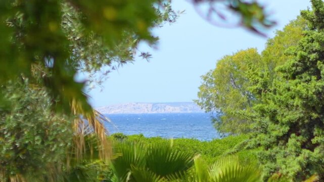 View of Kalymnos island from Kos, Greece, surrounded by trees and the sea in slow motion 60fps