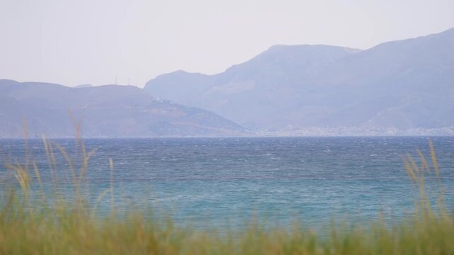 View of Kalymnos island from Kos, Greece, surrounded by trees and the sea in slow motion 60fps