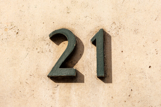 Num&eacute;ro d&rsquo;habitation 21 en m&eacute;tal sur fa&ccedil;ade beige textur&eacute;e