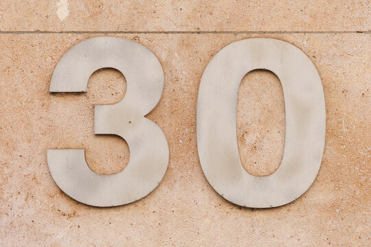 Num&eacute;ro d&rsquo;habitation 30 sur fa&ccedil;ade d&rsquo;immeuble beige textur&eacute;e