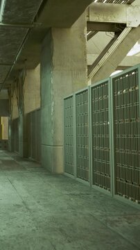 A large indoor area with concrete walls and a row of storage compartments on one side. A small plant adds a touch of nature along the wall.