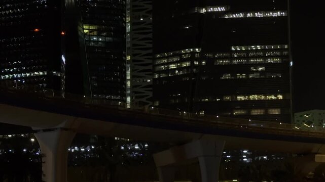 Riyadh, Saudi Arabia - July 2026: Riyadh Metro train passing on the bridge at night in front of illuminated skyscrapers at King Abdullah Financial District KAFD.