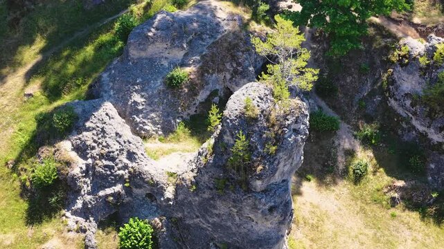 Luftaufnahme des Felsenmeers im Wental mit markanten Felsformationen aus Jurakalk, umgeben von einem dichten Nadelwald und Wanderwegen auf der Schw&auml;bischen Alb bei Sonnenschein.