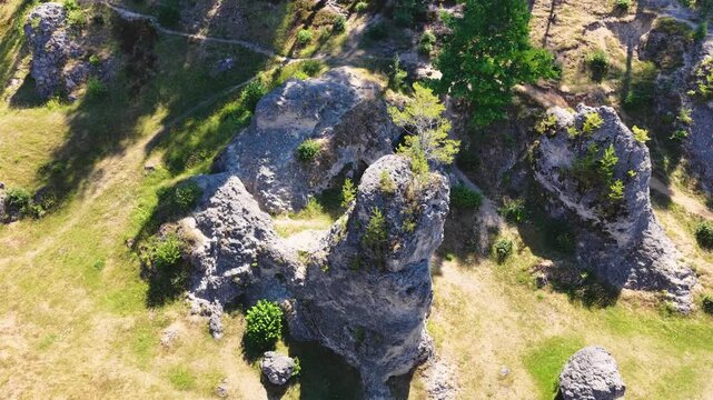 Luftaufnahme des Felsenmeers im Wental mit markanten Felsformationen aus Jurakalk, umgeben von einem dichten Nadelwald und Wanderwegen auf der Schw&auml;bischen Alb bei Sonnenschein.