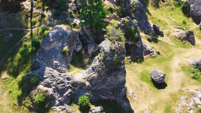 Luftaufnahme des Felsenmeers im Wental mit markanten Felsformationen aus Jurakalk, umgeben von einem dichten Nadelwald und Wanderwegen auf der Schw&auml;bischen Alb bei Sonnenschein.
