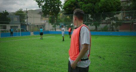 Fototapeta premium Latin Hispanic man standing on soccer field with arms crossed, looking serious and focused, expressing determination, confidence, and readiness during outdoor soccer training