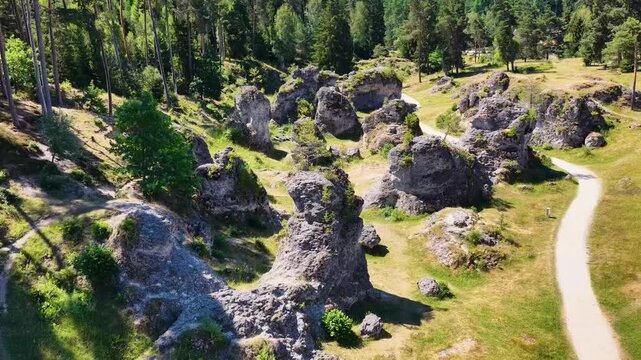 Luftaufnahme des Felsenmeers im Wental mit markanten Felsformationen aus Jurakalk, umgeben von einem dichten Nadelwald und Wanderwegen auf der Schw&auml;bischen Alb bei Sonnenschein.