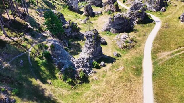 Luftaufnahme des Felsenmeers im Wental mit markanten Felsformationen aus Jurakalk, umgeben von einem dichten Nadelwald und Wanderwegen auf der Schw&auml;bischen Alb bei Sonnenschein.