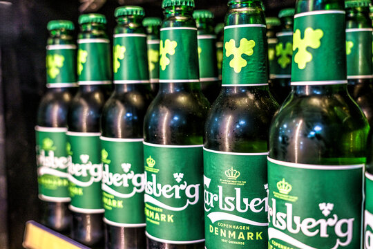 Carlsberg beer bottles lined up on a shelf, featuring green labels and caps, showcasing the brand's logo and Denmark origin in Antalya, Turkey