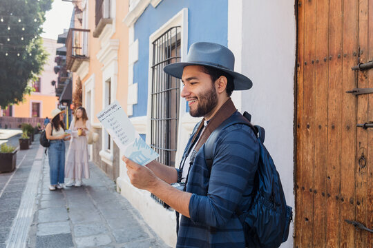 Latino man tourist or backpacker holding a touristic map in a traditional mexican colonial city in Mexico, Vacations at summer in latin america