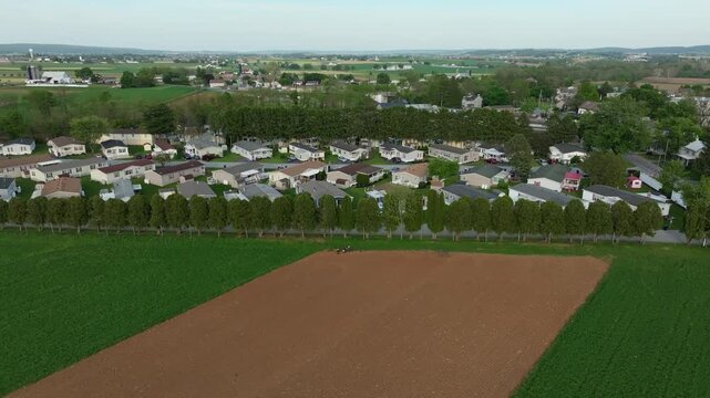 This captures a view of a Mobile Home Park where houses sit next to green fields. It shows the layout of the town and the farmland surrounding it. The setting displays typical rural life.