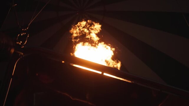 Slow motion in early morning darkness of hot air balloon fire, chemicals, liquid propane gas, and air rising as balloons rise for dusk ride through the sky on tourist adventure as flames shoot up 4k