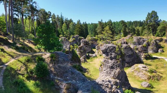 Luftaufnahme des Felsenmeers im Wental mit markanten Felsformationen aus Jurakalk, umgeben von einem dichten Nadelwald und Wanderwegen auf der Schw&auml;bischen Alb bei Sonnenschein.