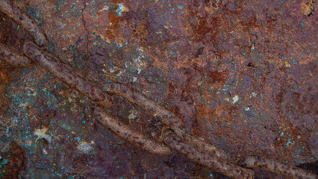Macro view of rusted iron surface intersected by a corroded chain at a coastal area