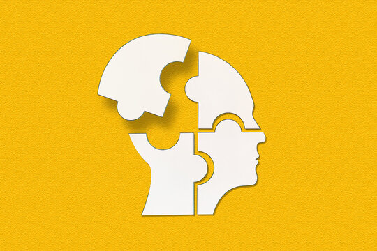 Mental health concept. Human head puzzle pieces on yellow background.	