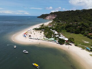 Aerial view of Praia da Gamboa with white sand, anchored boats, beach umbrellas, and tropical coastline in Bahia, Brazil © Luan