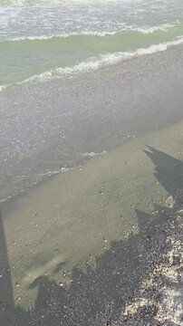 Sea waves washing on a sandy shore with beach umbrella shadows