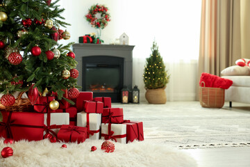 Obraz premium Many gift boxes and baubles under Christmas tree on floor indoors. Space for text