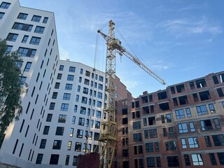 Fototapeta premium Exterior of building and construction crane under blue sky, low angle view