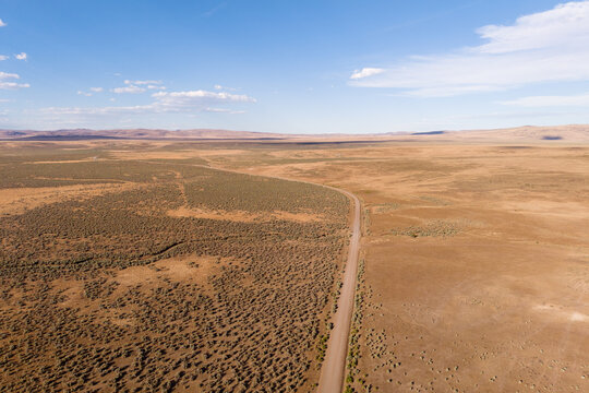 Aerial drone view of Smoke Creek Road stretching through the vast sagebrush high desert of Lassen County, California near the Nevada state line.