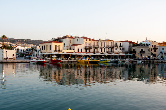 The picturesque Venetian harbour of Rethymno with waterfront tavernas, fishing boats and calm reflections on the island of Crete in Greece.