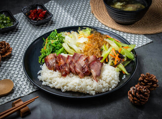 Fototapeta premium Roasted pork rice bowl with vegetables. Traditional Chinese BBQ pork served with steamed rice.