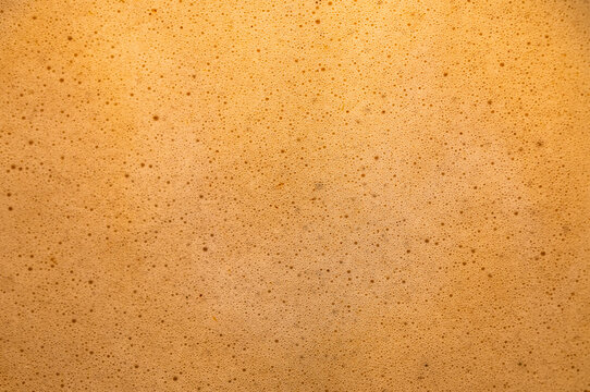 Texture of creamy cappuccino milk foam surface as gourmet coffee background for cafe beverage and barista concepts.