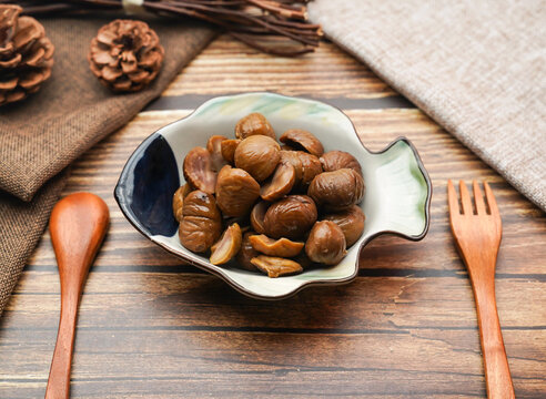 Sweet glazed chestnuts in a fish bowl. Delicious candied chestnut dessert on wooden table.