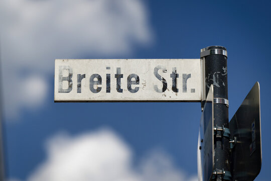 Close-up of the official German street sign for Breite Str in the city center of Cologne, Germany, with blue sky and white clouds background
