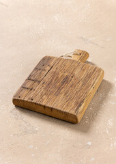 Obraz premium Empty Vintage Wooden Cutting Board on Beige Kitchen Table
