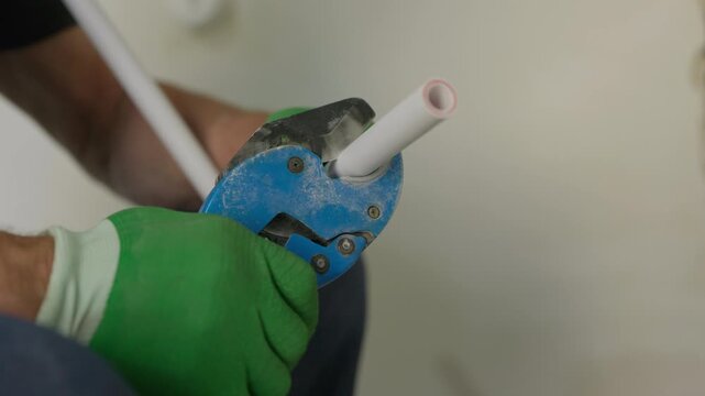 Cutting polypropylene pipe with pipe shears during plumbing work