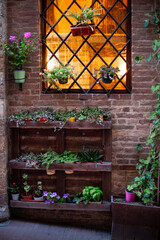 Obraz premium Potted plants decorating brick wall window with metal grate