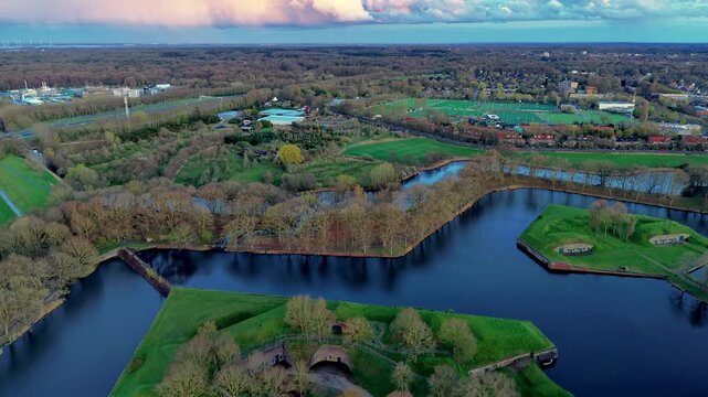 Aerial wide angle panoramic view of a historic medieval town border and its star fort fortress with complex zig-zag moats green ramparts and classic houses under a sunset sky